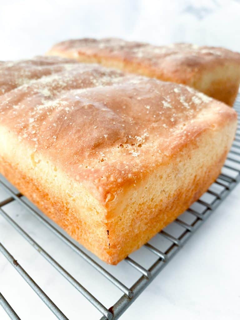 Whole english muffin loaf on a wire rack cooling