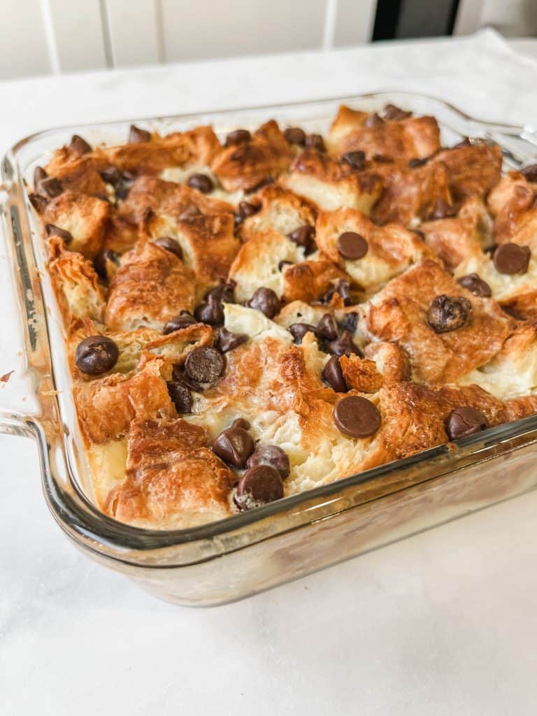Croissant French toast baked in a casserole dish topped with chocolate chips.