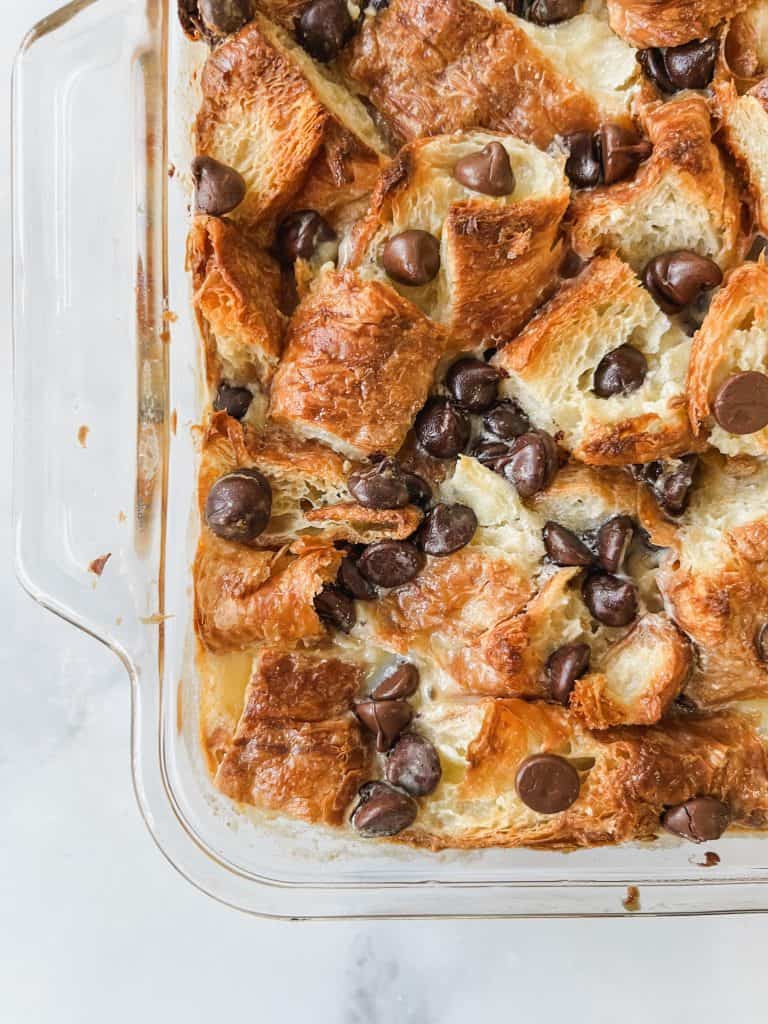 Croissant French toast baked in a casserole dish topped with chocolate chips.