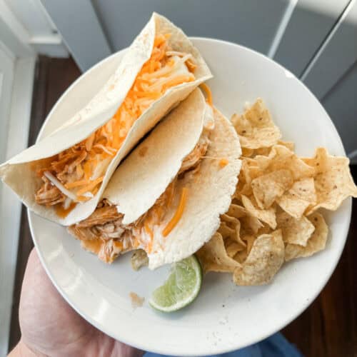 overhead photo of 2 tacos with lime wedge and chips. 2 Ingredient Taco Chicken