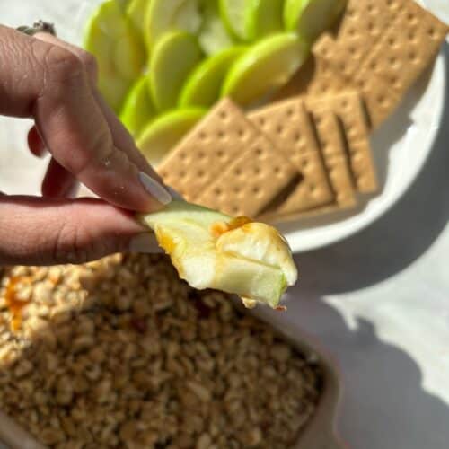 caramel apple cheesecake dip on a slice of a green apple