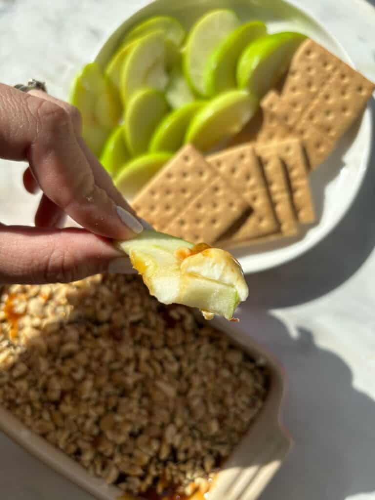 caramel apple cheesecake dip on a slice of a green apple