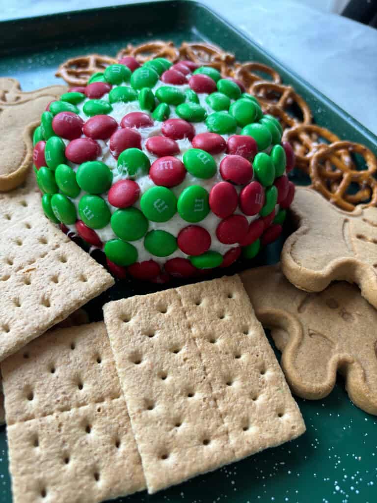 side view of a dessert dip with M&M'S, graham crackers, pretzels and gingerbread men.
